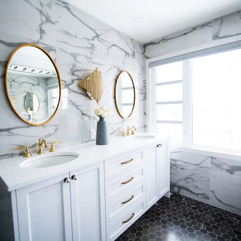 Stunning marble bathroom with brass taps and oval mirrors and hexagon tiled floor