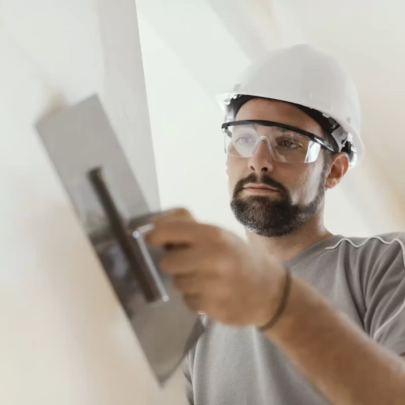 Plaster finish by man with hard white hat and trowel in the lounge